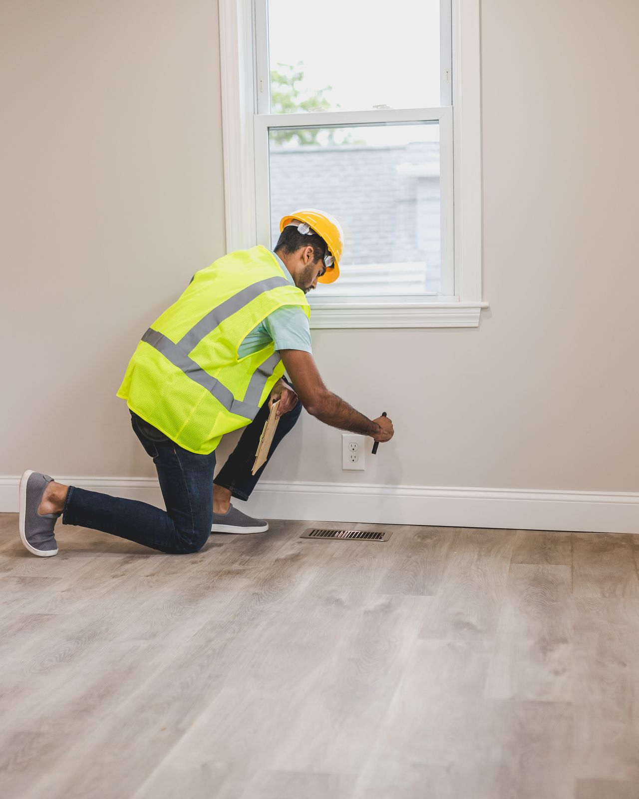 Contractor kneeling on new flooring while working during a home renovation